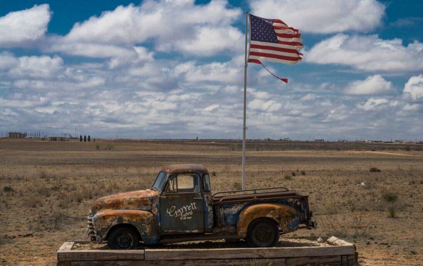 Deserted pickup truck display and US flag at Garrett Farms, outside of Midland, Texas.